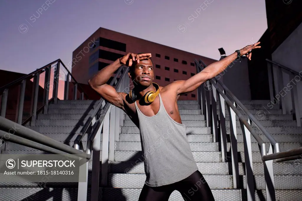 Young man in dab pose while standing on metal staircase