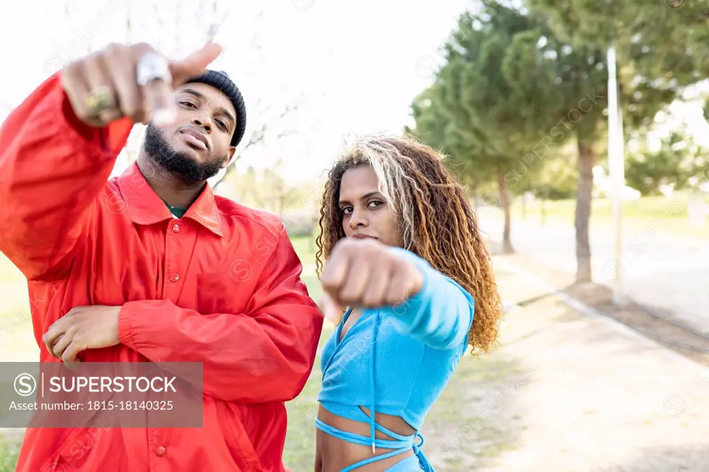 Female and male friends gesturing while standing in park