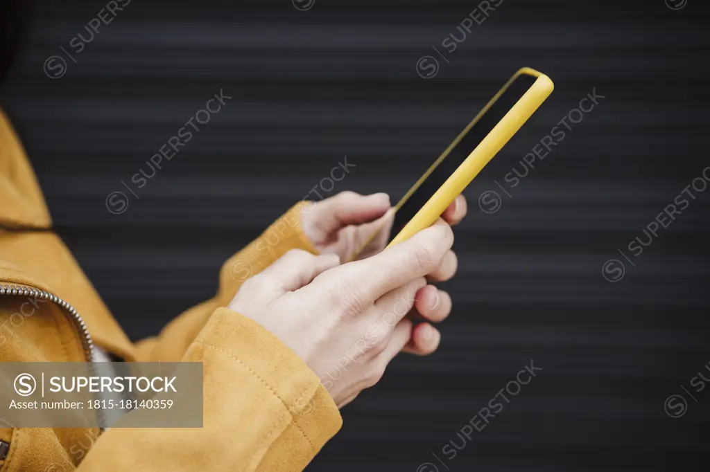 Mid adult woman using mobile phone by black wall