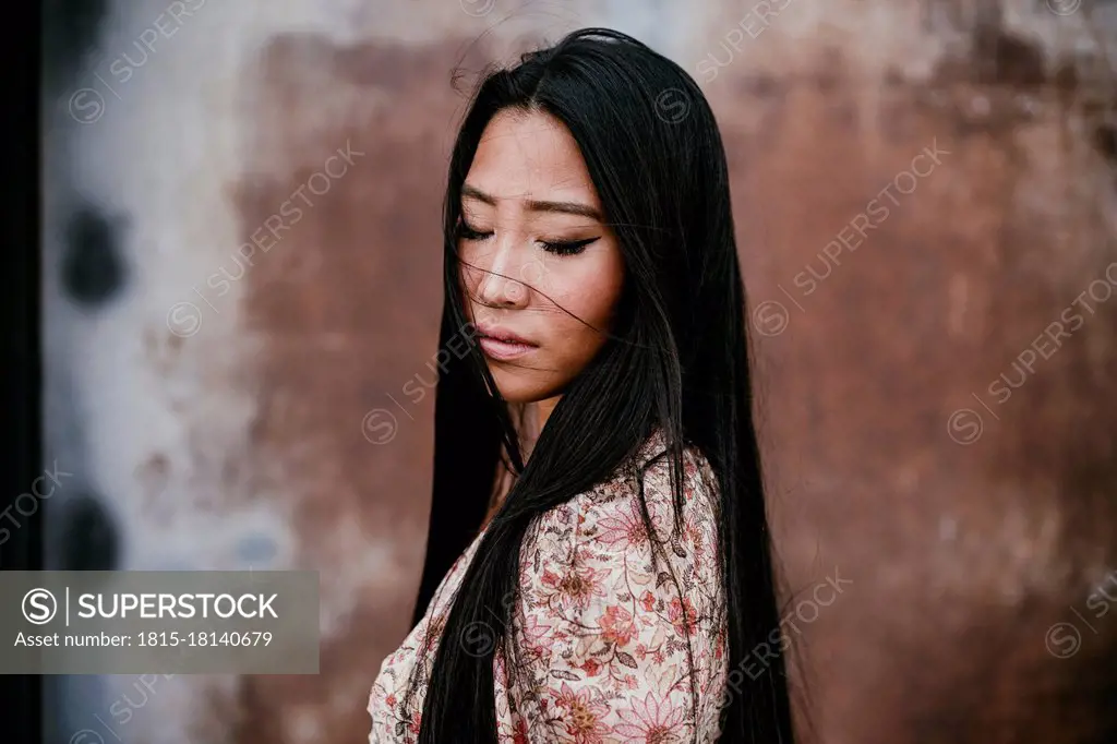 Beautiful woman with eyes closed by rusty iron door