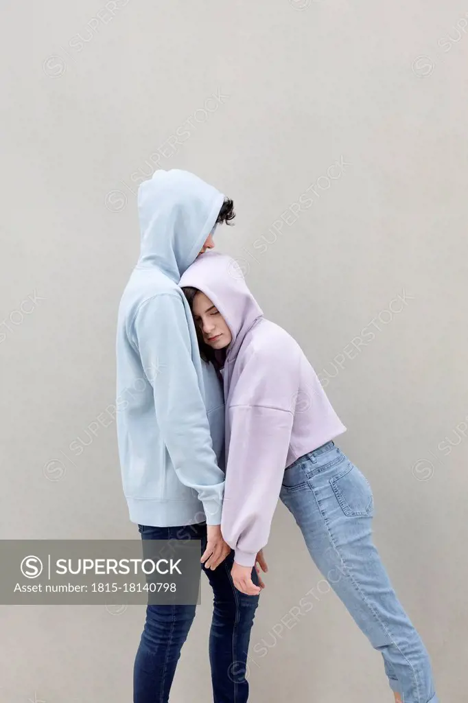 Teenage girl leaning on boyfriend by wall