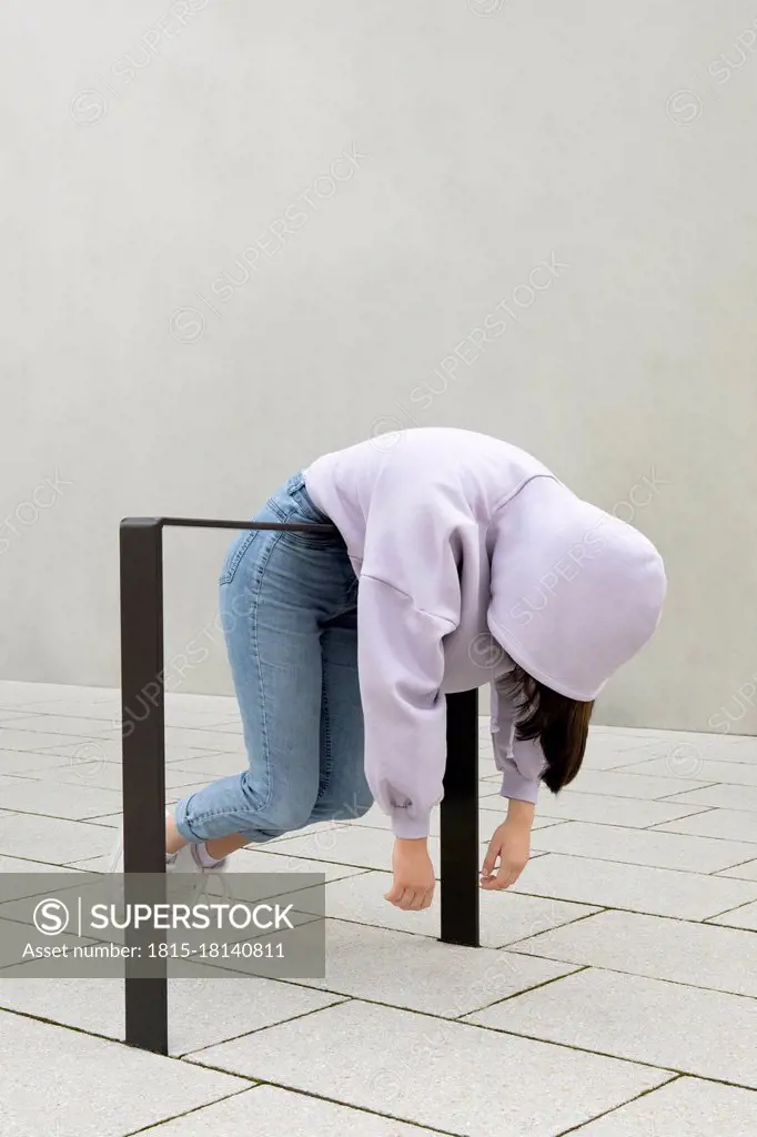 Girl hanging on metal by wall