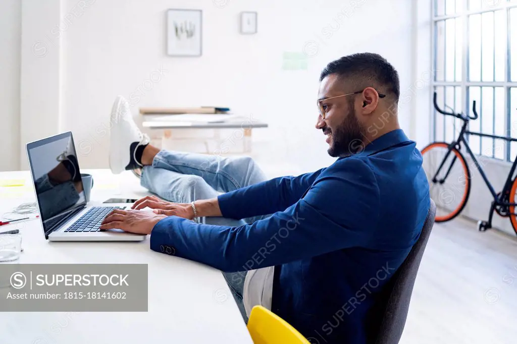 Relaxed businessman working on laptop in modern office