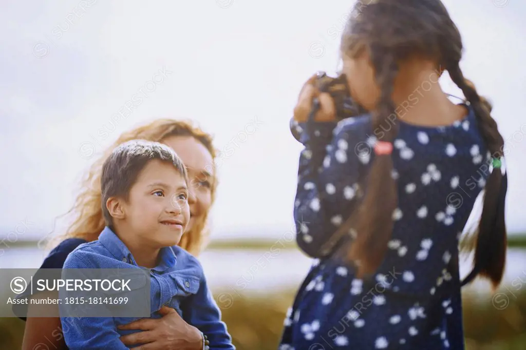 Girl photographing mother and brother