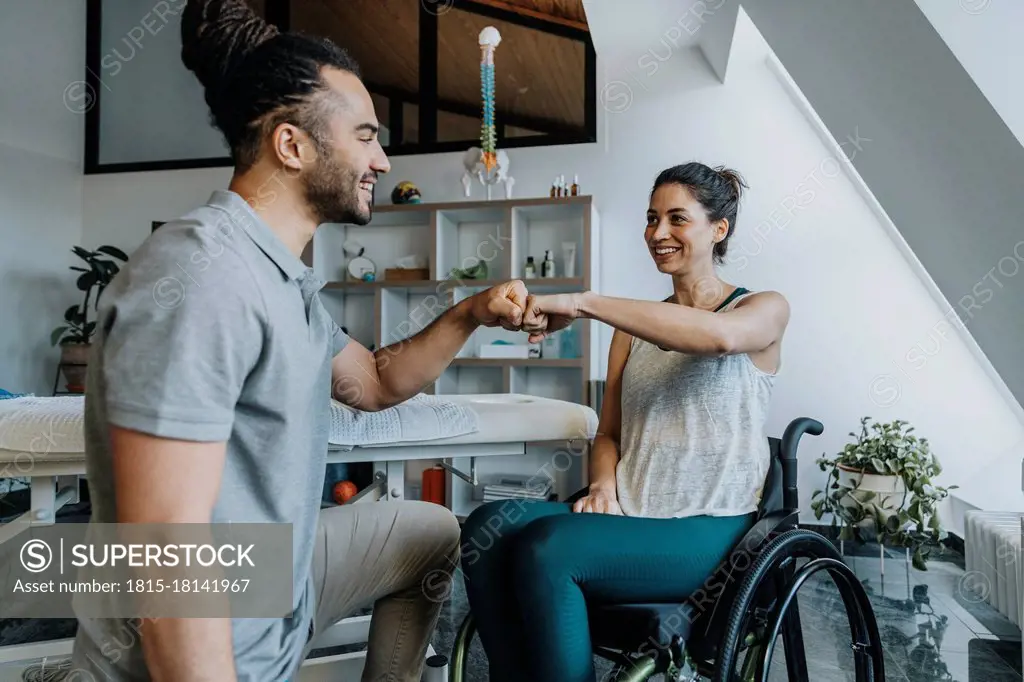 Happy physiotherapist giving fist bump to female patient