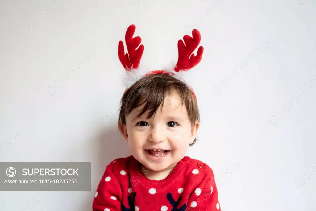 Portrait of laughing baby girl wearing reindeer antlers headband