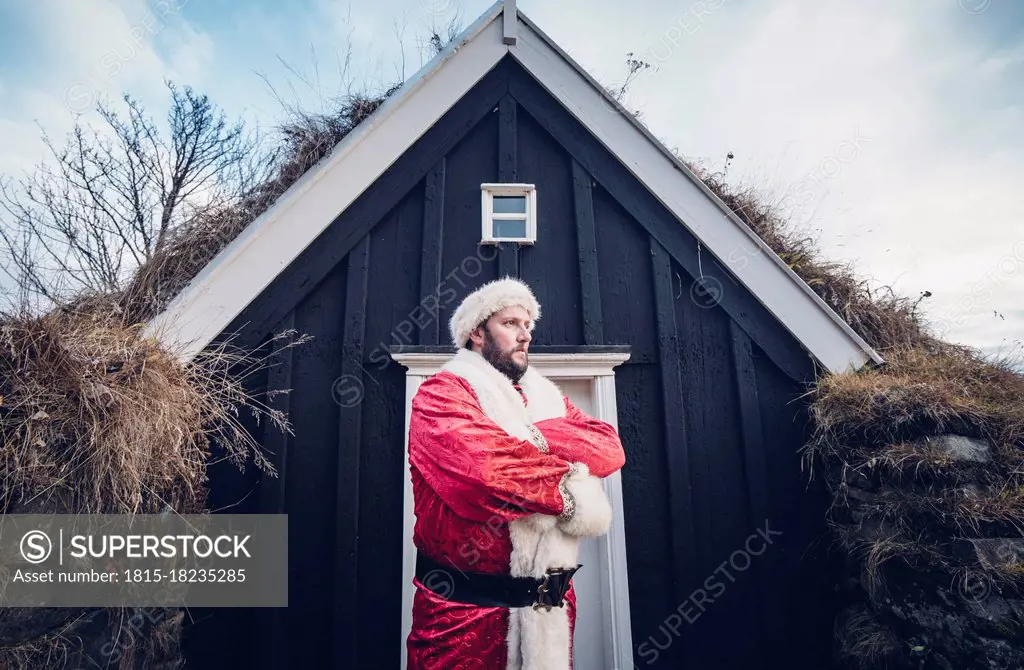 Iceland, Santa Claus standing in front of cabin looking at distance