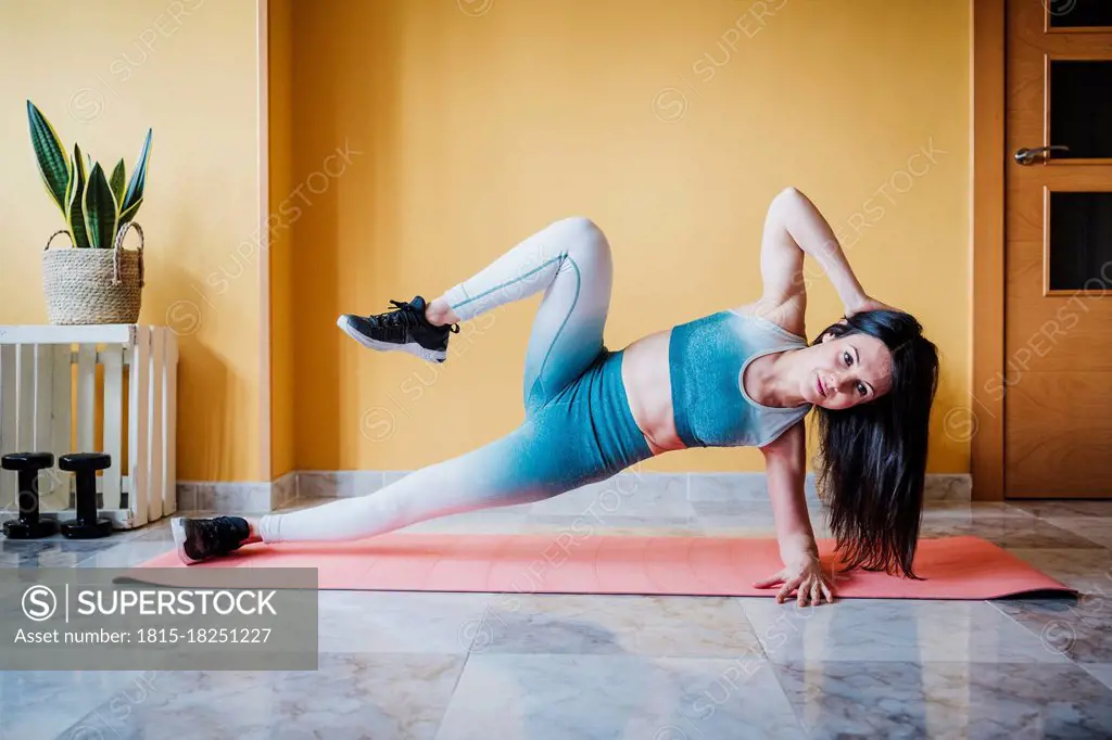 Sportswoman practicing strength training exercise on mat at home