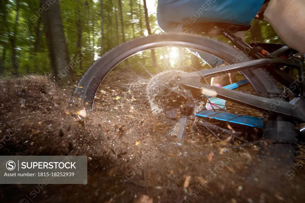 Rear wheel of bicycle drifting in dirt road at forest