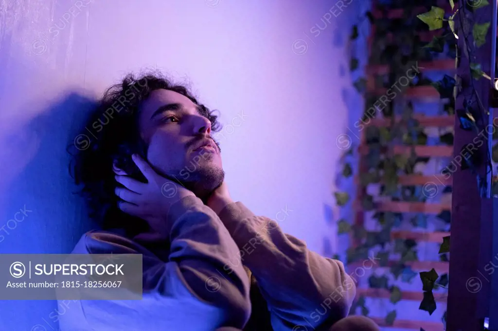 Depressed young man leaning on wall at home