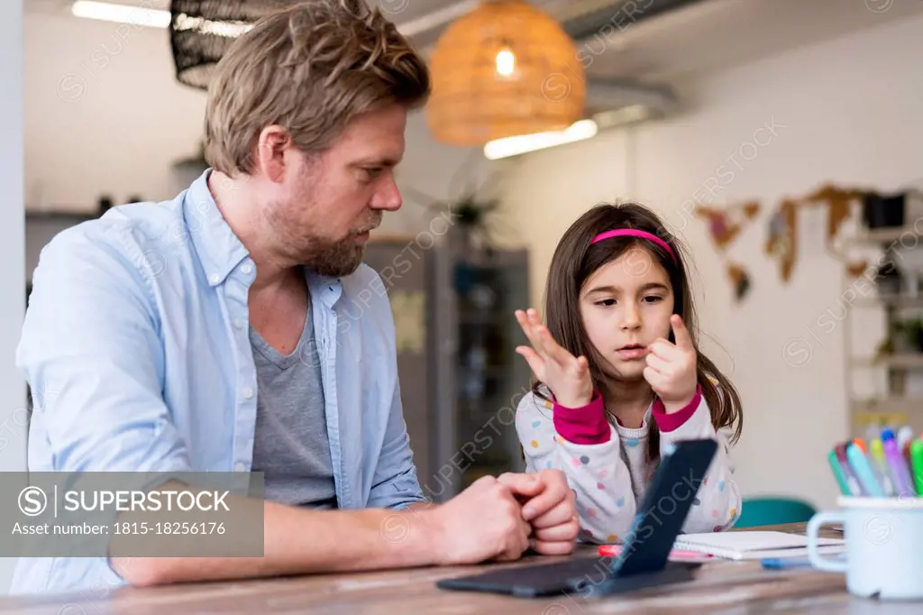 Girl counting fingers while sitting by father at home