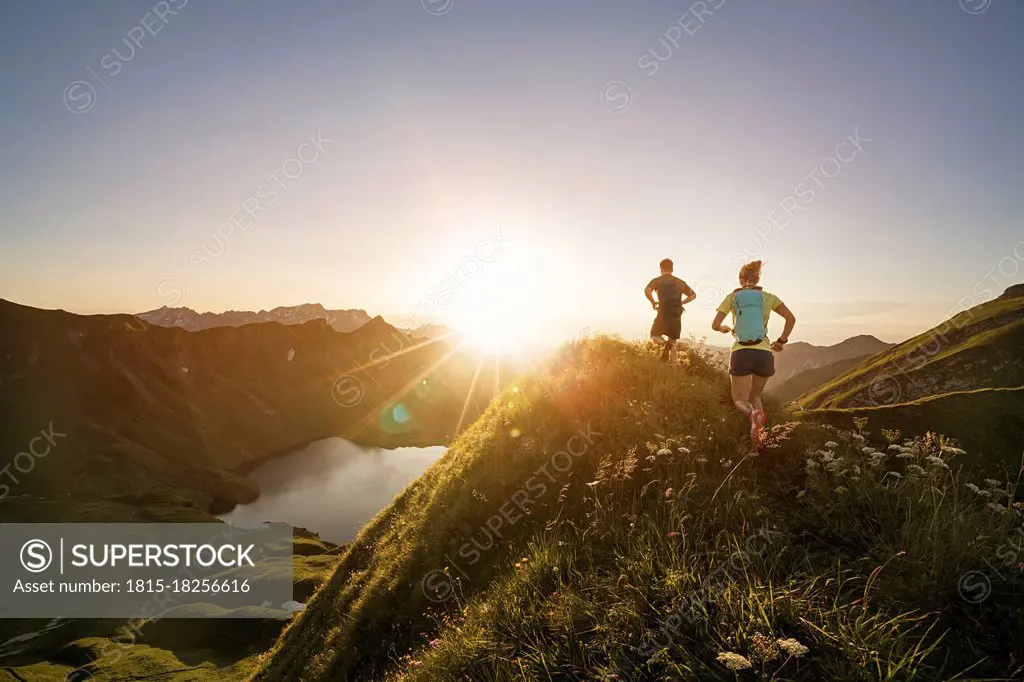 Germany, Allgaeu Alps, man and woman running on mountain trail