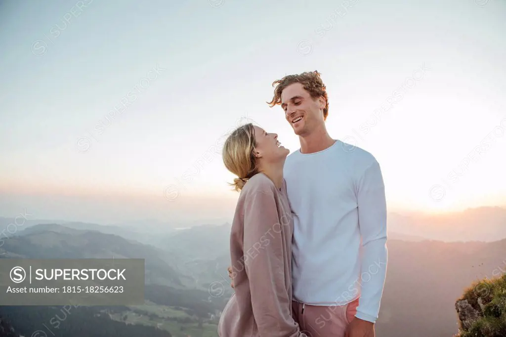 Switzerland, Grosser Mythen, happy young couple standing in mountainscape at sunrise