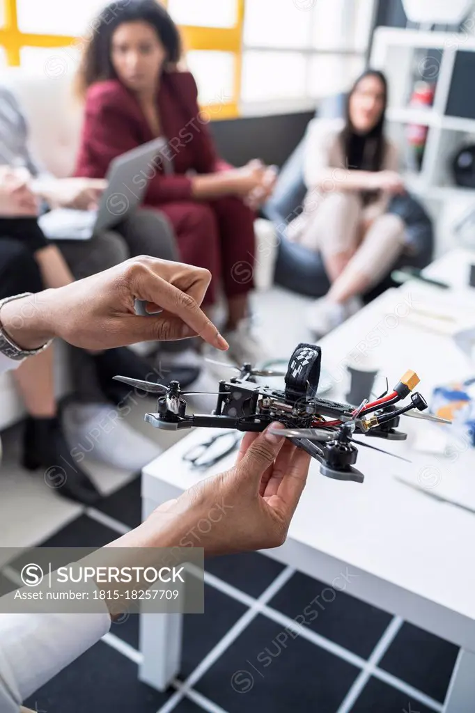 Male engineers explaining drone model with colleagues in office