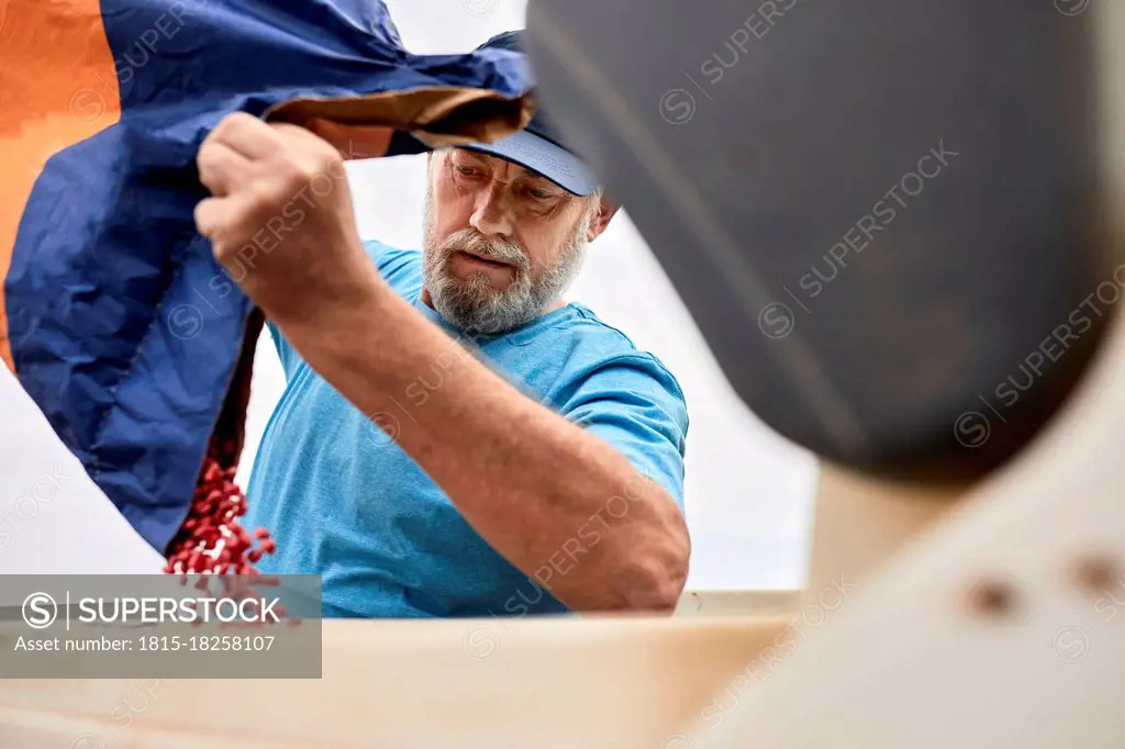 Mature male farmer pouring corn seeds in container at farm