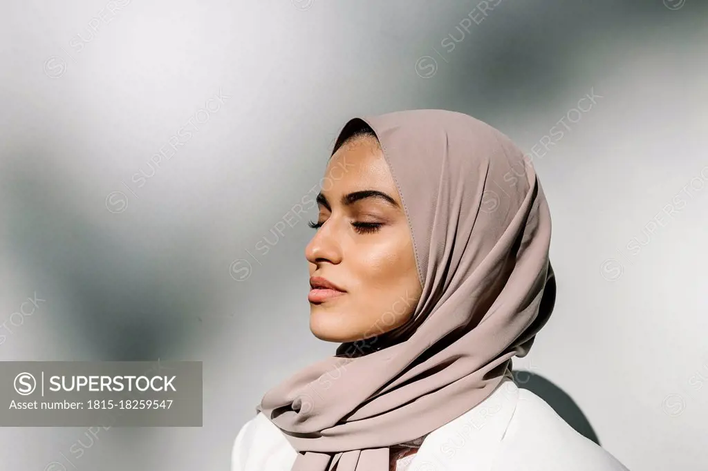 Young woman with eyes closed in front of white wall