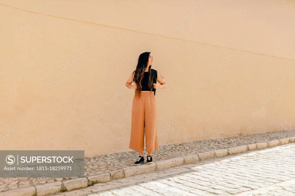 Female tourist looking away while standing on footpath