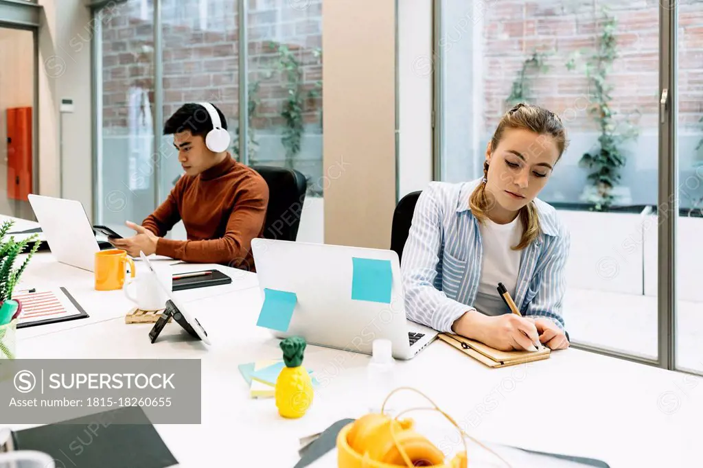 Colleagues working while sitting at office