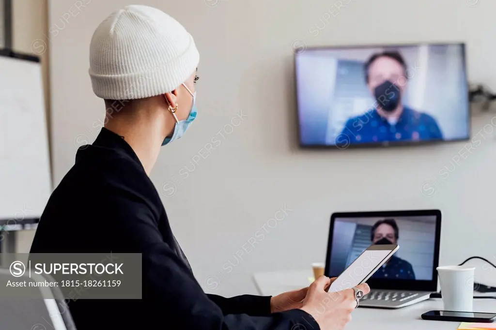 Businesswoman attending meeting through video call with colleague in office during COVID-19