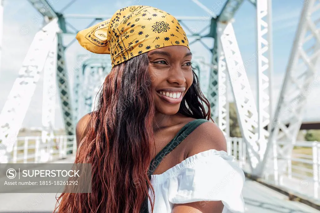 Smiling woman with bandana looking away at bridge