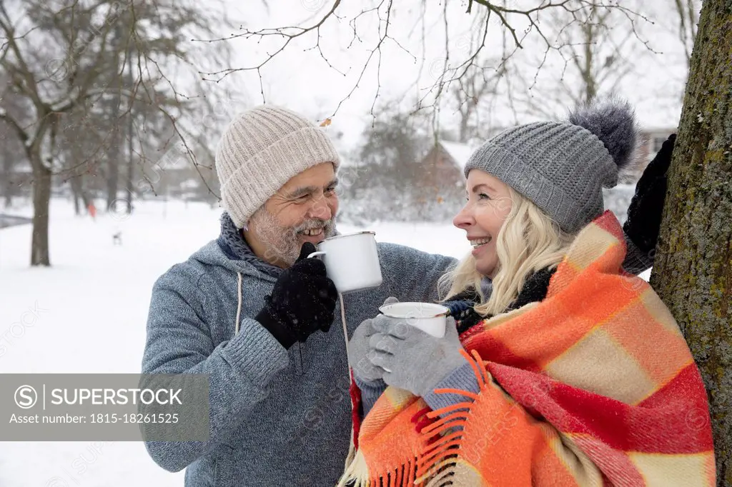 Smiling senior couple drinking tea in mug during winter