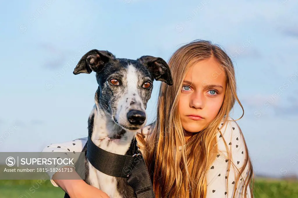 Blond girl with greyhound looking away