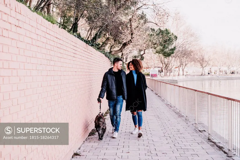 Young couple walking with dog on footpath