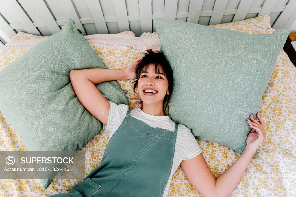 Thoughtful woman smiling while lying on bed