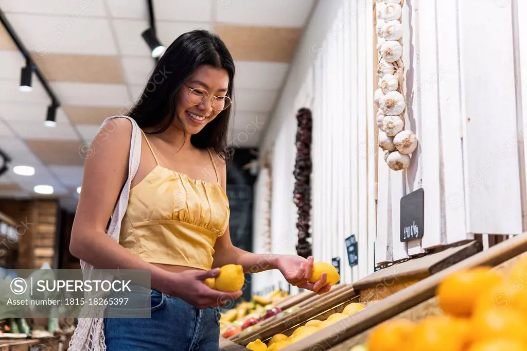 Smiling woman buying lemons at grocery store