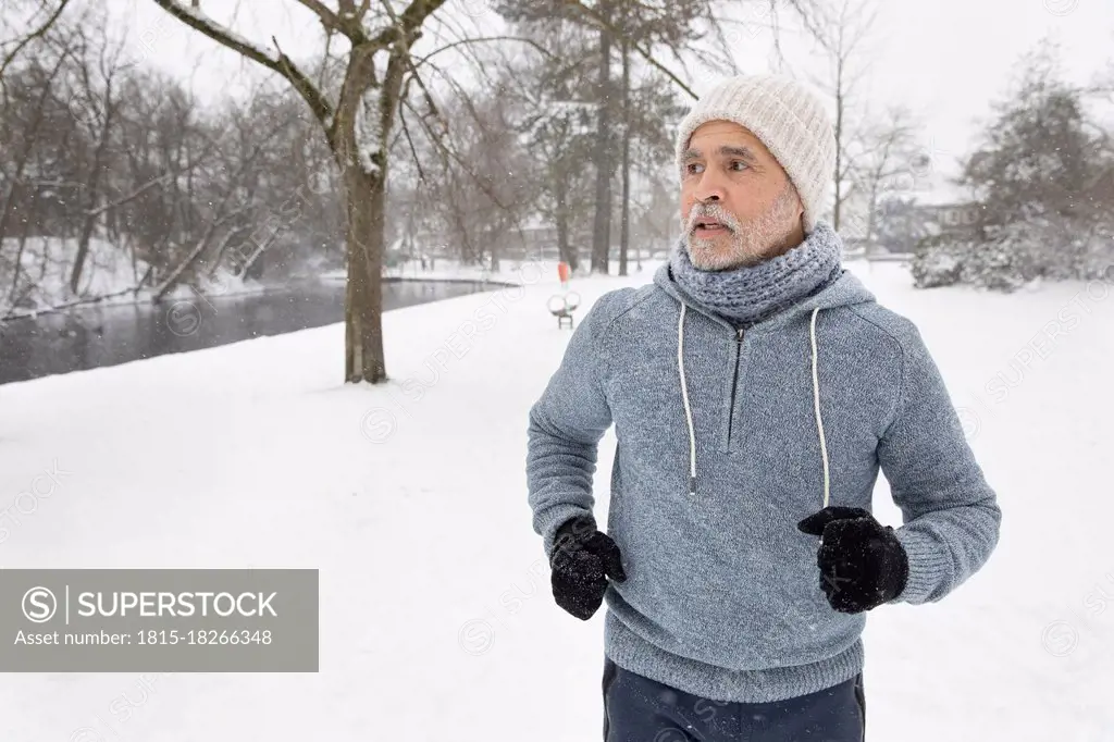 Senior man looking away while running at park during winter