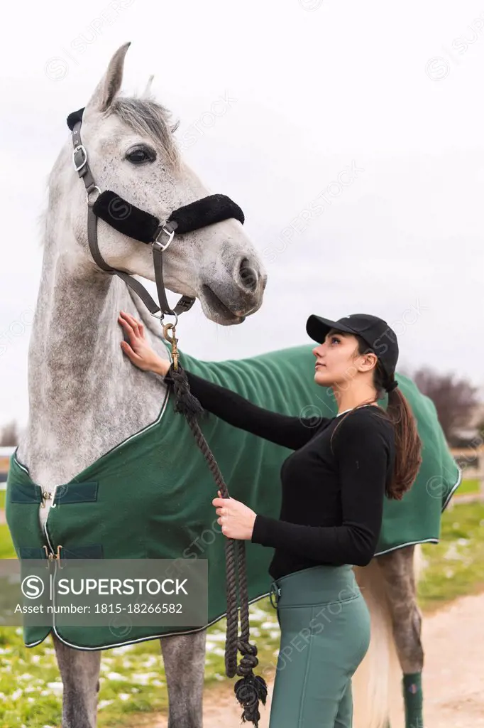 Young woman stroking horse outdoors