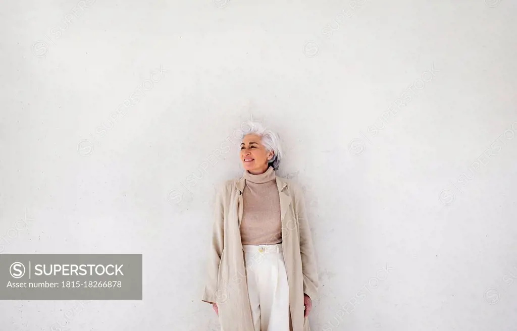 Smiling woman standing in front of white wall