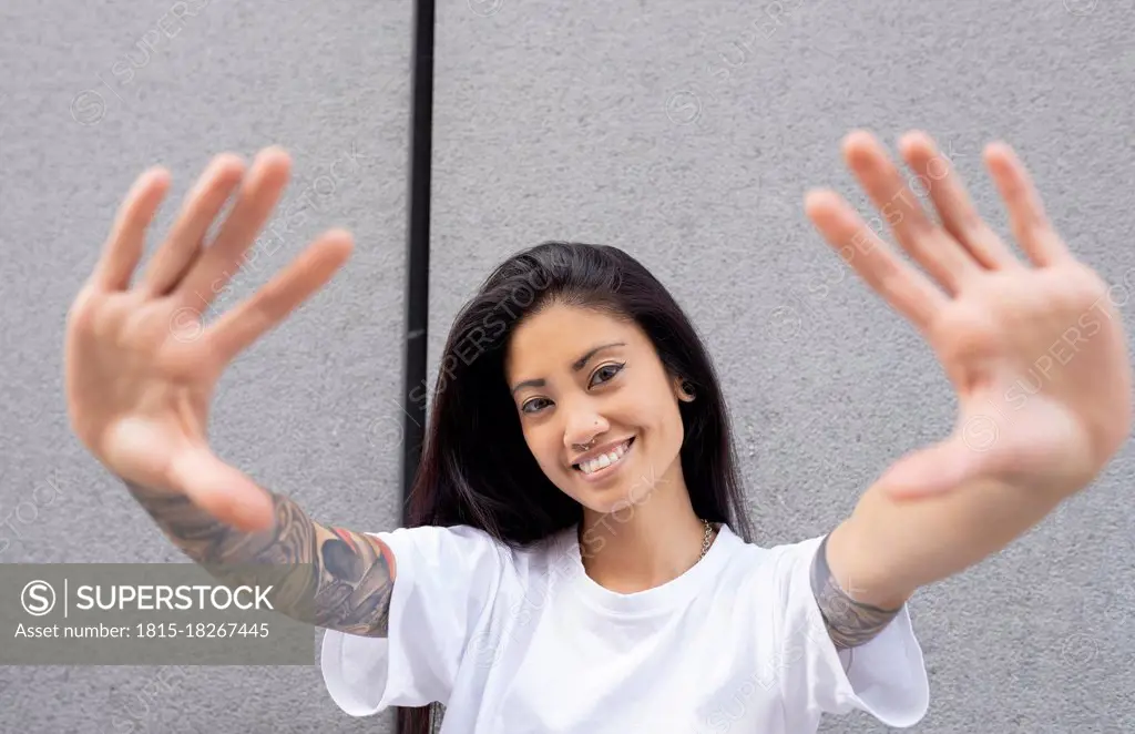 Hipster woman showing hands by wall