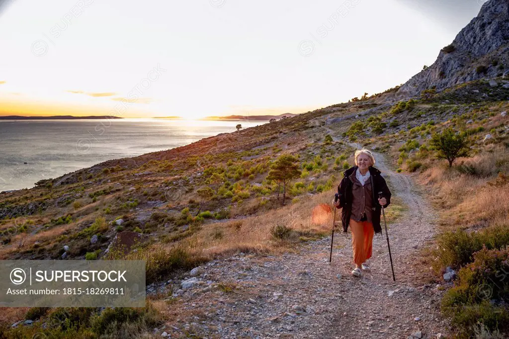 Senior woman with hiking poles on footpath near Adriatic sea in Omis, Dalmatia, Croatia