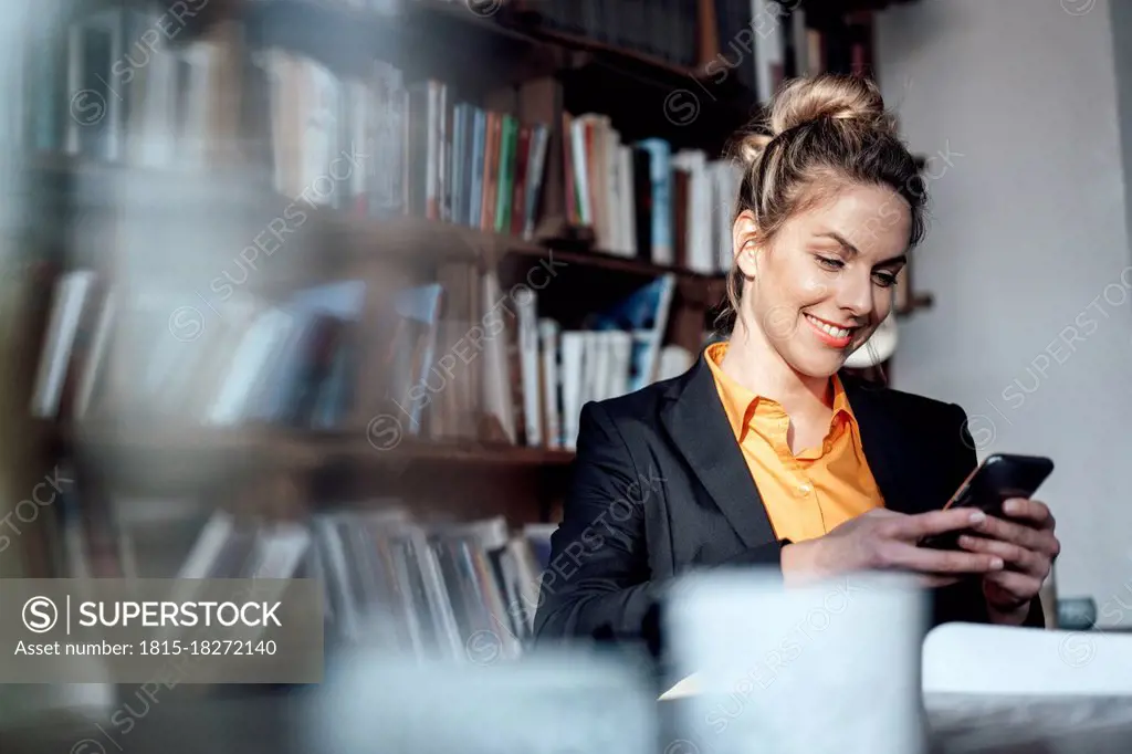 Mid adult businesswoman using mobile phone at coffee shop