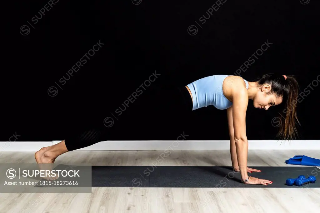 Female sportsperson doing push-ups on exercise mat in studio