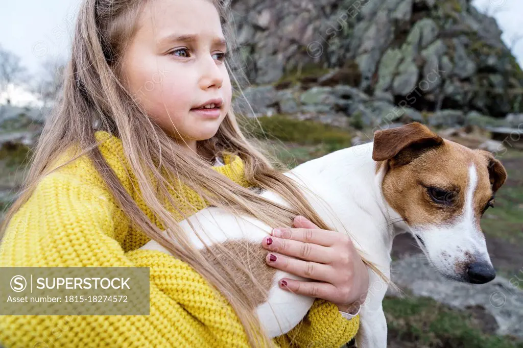 Blond girl carrying Jack Russell Terrier looking away