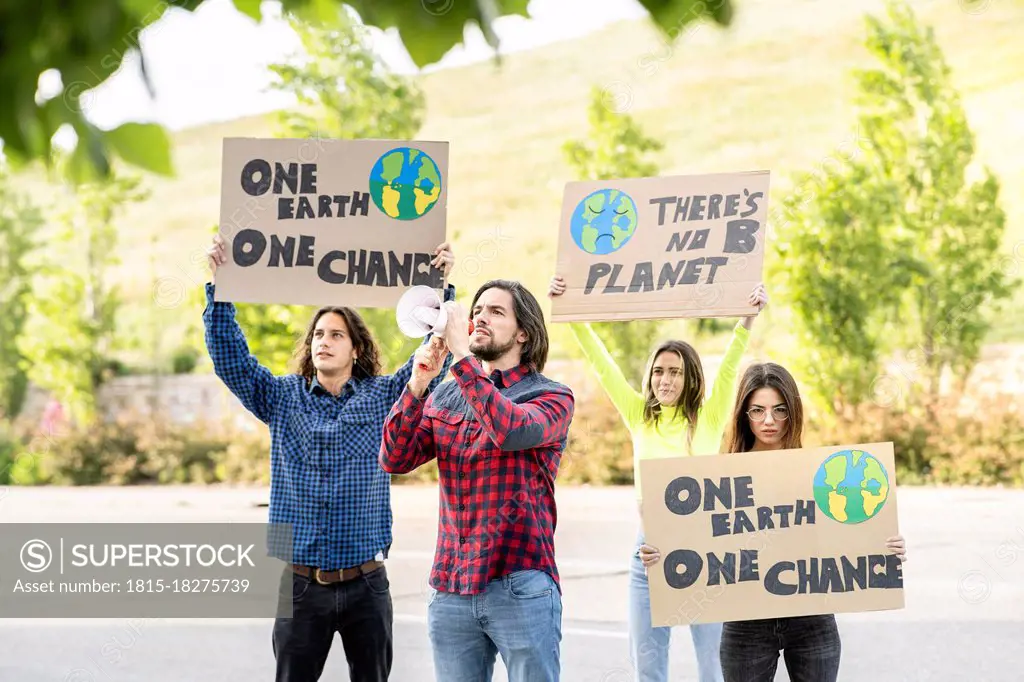 Male and female protestors with poster alerting on climate change at footpath