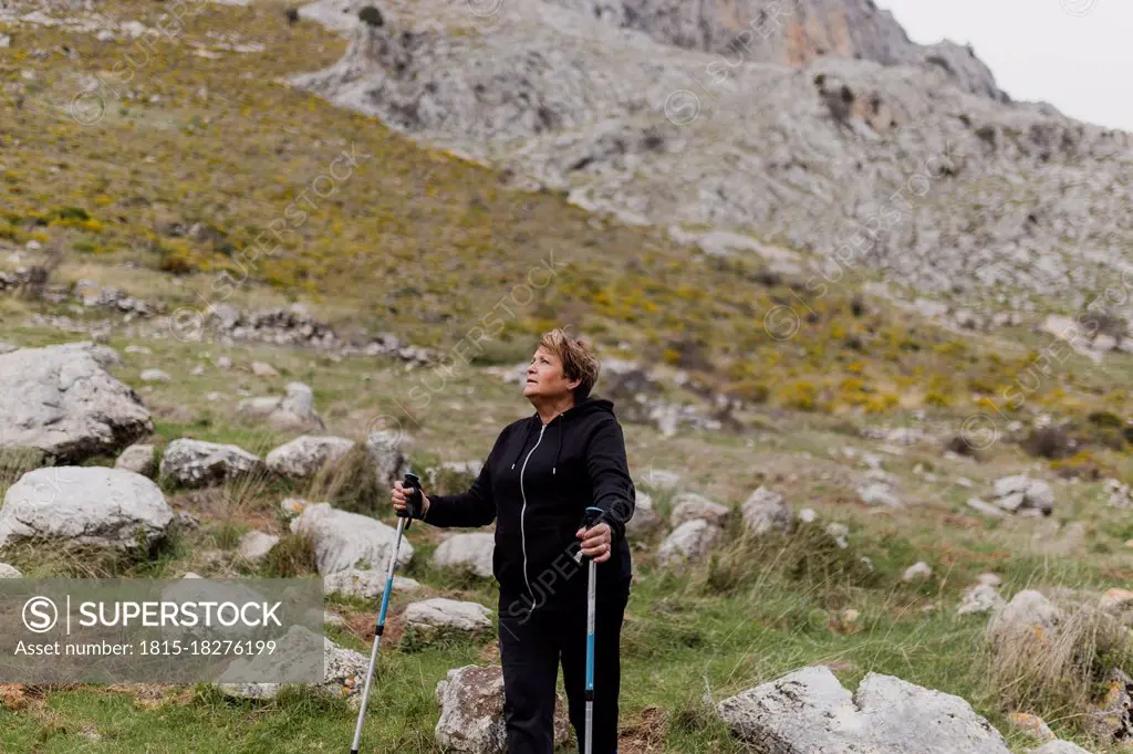 Senior woman in sports clothing hiking on mountain