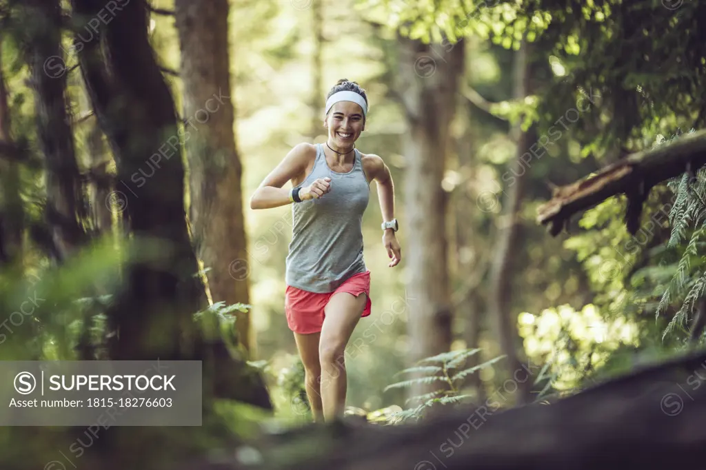 Excited female athlete running in forest