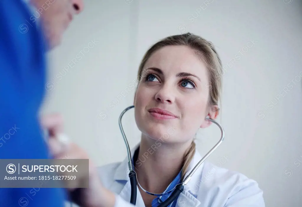 Female doctor checking senior patient with stethoscope in hospital