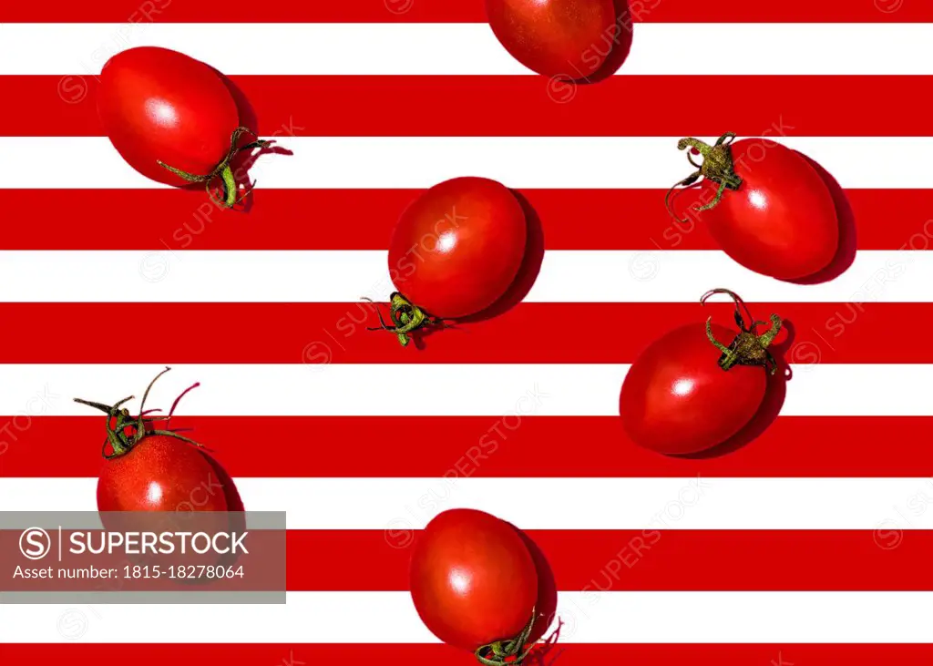 Studio shot of cherry tomatoes lying against white and red striped background