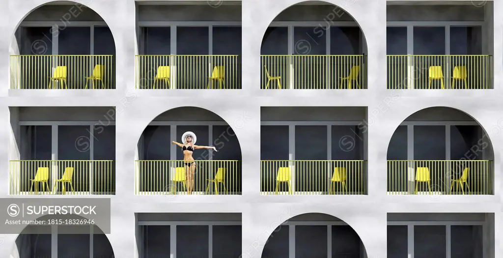 Woman wearing bikini standing in balcony of hotel during vacation