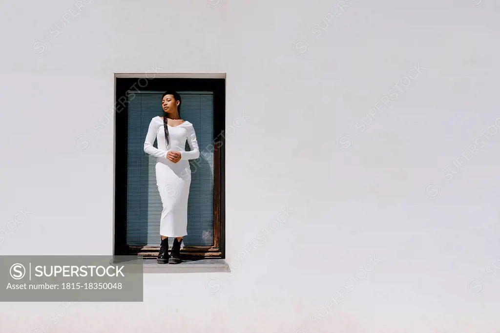 Woman with eyes closed standing on window sill