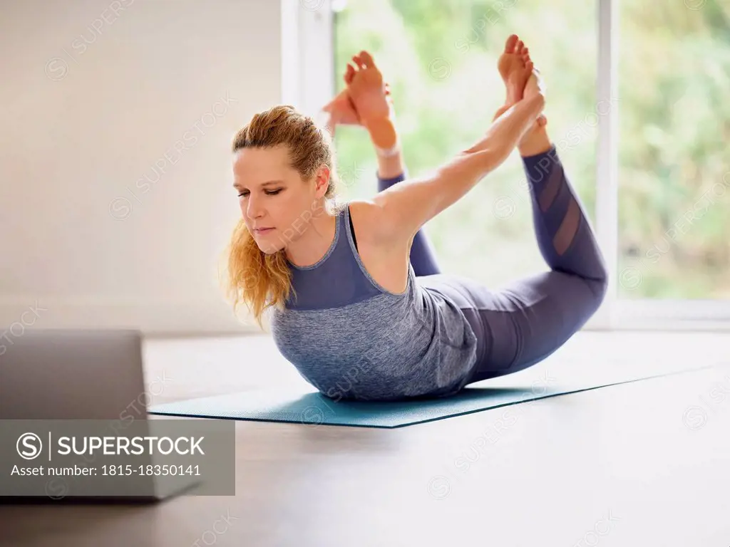 Mature woman doing Dhanurasana at home