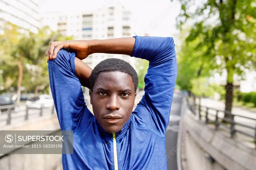 Afro man stretching arms in city