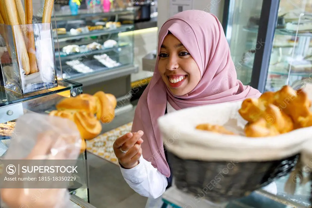 Happy woman buying pastry in bakery