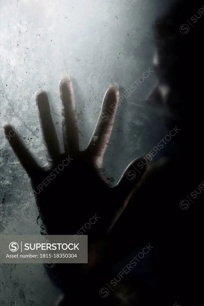 Silhouette hand on frosted glass