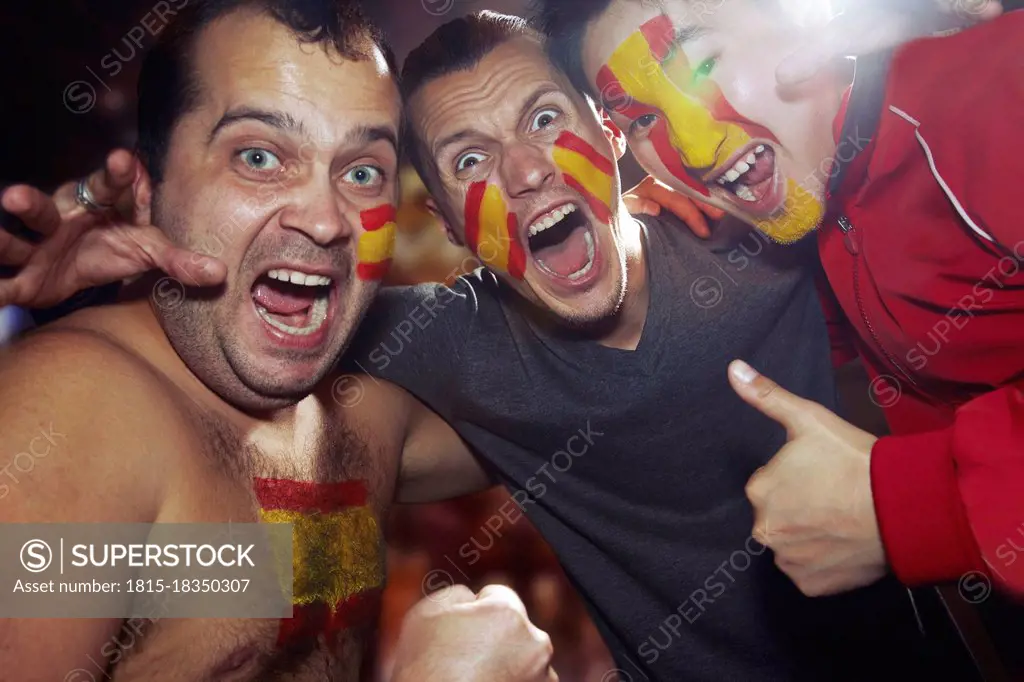 Male sports fan with Spanish flag paint on face