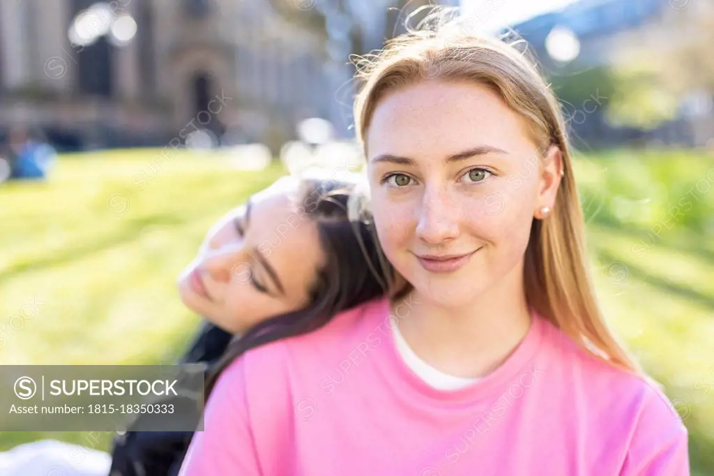 Beautiful blond woman with head on shoulder of female friend in public park